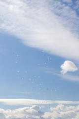 Naklejka na ściany i meble Colorful balloons fly in the blue spring sky with white clouds