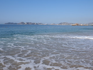 Beautiful panorama of Pacific Ocean waves on sandy beach at bay of ACAPULCO city in Mexico