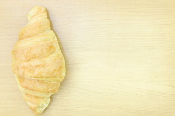 Close up single brown croissant bread on wooden table background have copy space for put text, French bakery style, Top view