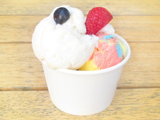 Mix blueberry and strawberry ice cream on top in white paper bowl on wood table background