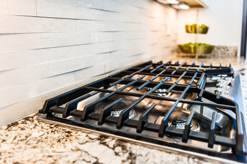 Macro closeup of modern luxury gas stove top with tiled backsplash