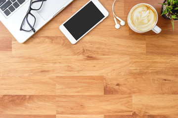 Wood office desk table with laptop computer, smartphone and supplies. Top view, flat lay.