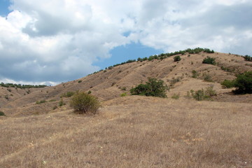 Panorama of the poor nature of the sandy Crimean mountains against the background of the cloudy sky.