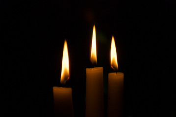 three candles burn in the dark