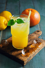 Refreshing fruit drink detox. Summer orange lemon cocktail with ice and mint close up. Dietary fruit drink with backlight on a wooden rustic table.