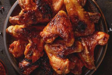 Barbecued chicken wings with bbq sauce on the plate top view.