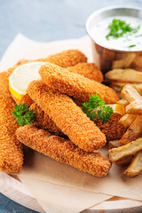 Fish fingers and fries with sauce on dark background. 