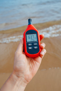 portable thermometer in hand measuring outdoor air temperature and humidity