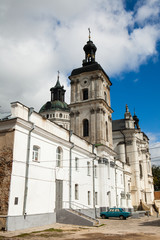 Ancient monastery of Discalced Carmelites, cathedral and fortress wall on background of blue cloudy sky. Berdychiv, Ukraine. Tourist attraction. Place of visit by Pope John Paul II