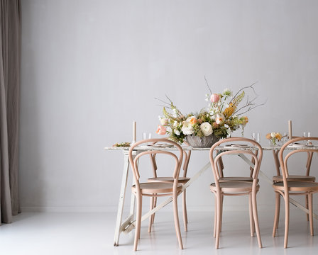festlich gedeckter Tisch mit Blumen in hellem Raum