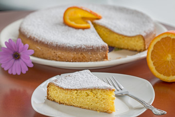 Homemade orange pie slice. Background: orange pie and a flower.