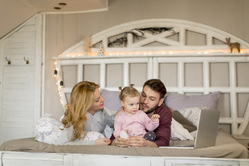 Loving family looking at a laptop lying down on bed in bedroom