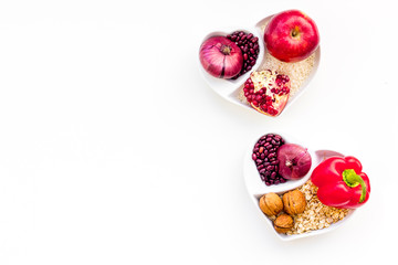 Diet for healthy heart. Food with antioxidants. Vegetables, fruits, nuts in heart shaped bowl on white background top view copy space