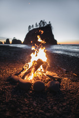 Fire on the beach with rock formation and evening glow in the background small waves entering the beach near La Push, USA