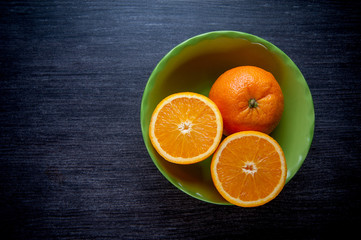 oranges in a green plate and on a dark table