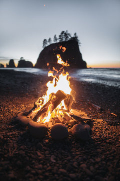 Bonfire on the beach with rock formation in background at sunset, USA