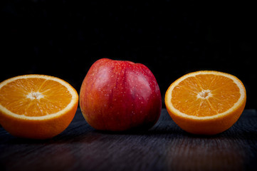 useful vitaminized food lies on a dark table, an orange and an apple