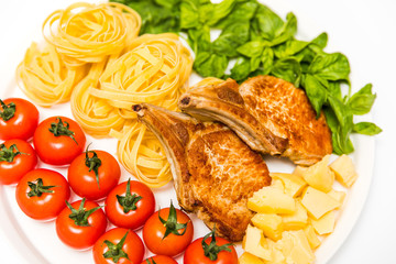 Fried pork ribs with spaghetti, cherry tomatoes, basil, olives and cheese