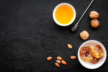 Fresh honey as dessert. Honey in bowl, honeycomb, nuts on black table top view copy space