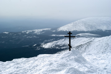 Naklejka na ściany i meble orthodox cross on top of the mount Konzhakovskiy Kamen against the background of the surrounding winter mountains