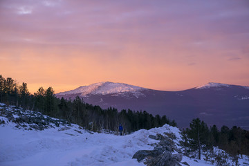 winter dawn mountain landscape with a hiker girl walking along the road