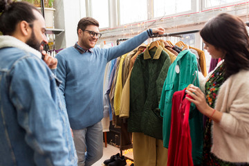 sale, shopping, fashion and people concept - friends choosing clothes at vintage clothing store