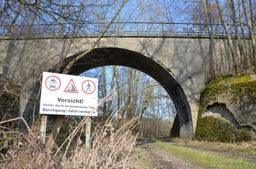 Abandoned train bridge near Isen, Germany with a warning sign in the front