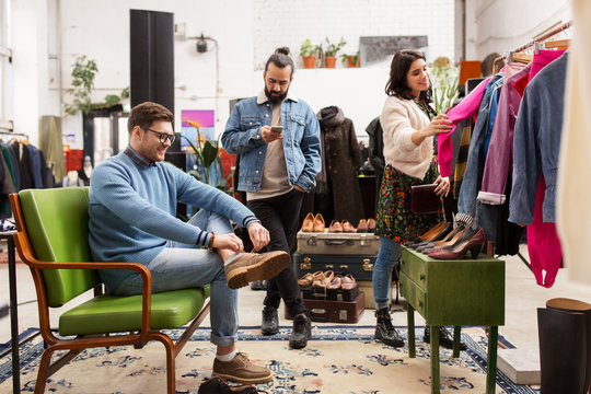 sale, shopping, fashion and people concept - friends choosing clothes and footwear at vintage clothing store