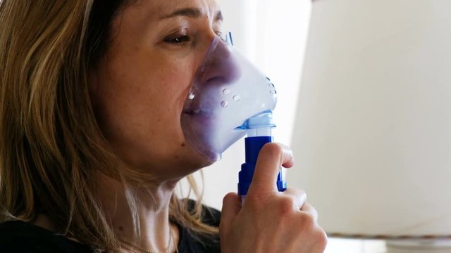coughing woman with nebulizer  aerosol  inhaler mask to cure respiratory seasonal flu
