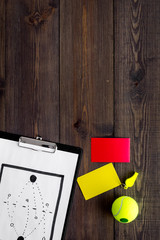 Sport judging concept. Tennis referee. Tactic plan for game, tennis ball, red and yellow cards, whistle on wooden background top view copy space
