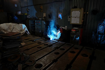 The welding welder is engaged in the manufacture of parts welding with sparks.