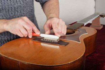 Guitar repair and service - Worker sharpen special tool bridge servo nut