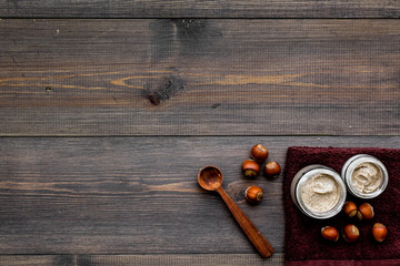 Treatment set with natural hazelnut scrub to take bath on wooden background top view mock-up