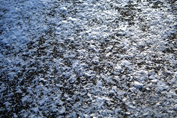 Fragments of snow on the ground in a clear frosty day. Sharp snowflakes. Crystals.