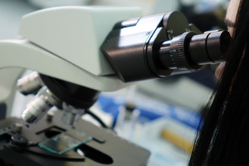 The girl-laboratory assistant works with a microscope in the laboratory.