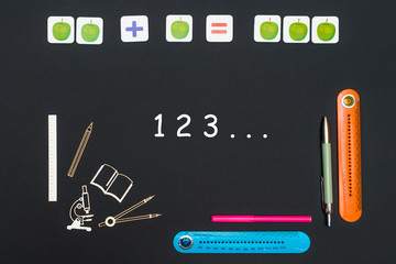Black art table with stationery supplies with numbers 1 2 3 on black background