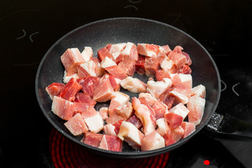Red meat on a frying pan on black cooking plate