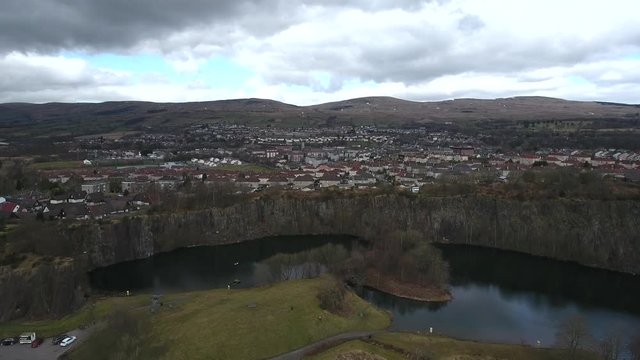 Aerial footage looking over the water filled Auchinstarry Quarry at Kilsyth, Scotland, UK.  Popular location for rock climbing. 