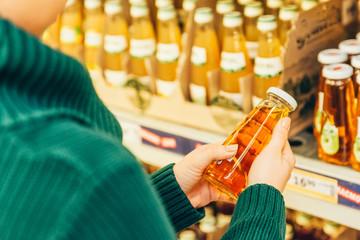 woman in store read ingredients of juice. grocery shopping. copy space