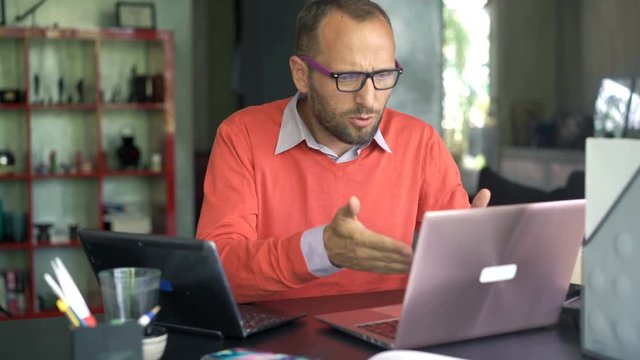 Unhappy, upset man having problems during work on laptops at home
