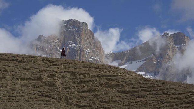 Woman in a poncho goes down a hill in a canyon