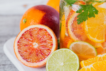 Citrus fruit and herbs water for detox or dieting in glass bottles. Limes and oranges