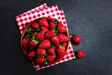 Strawberry. Fresh strawberry on black background with copy space for text. Heap of Red strewberry on a plate close up.