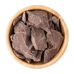 Cocoa mass in a wooden bowl isolated on white.