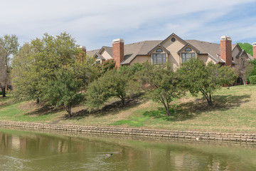 Fototapeta na wymiar Riverside home, apartment with green oak trees in Irving, Texas, USA. Ducks swimming on canal.