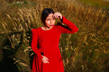 Young woman in a red dress in a wheat field.