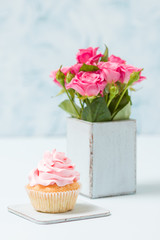 Cupcake with pink decoration and bouquet of pink roses in retro shabby chic vase.