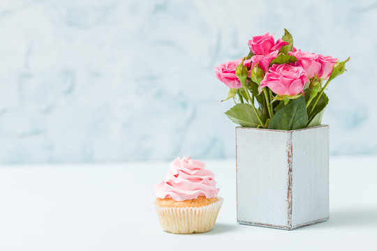Cupcake with cream decoration and pink roses in retro shabby chic vase.