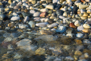 pebble stones on the sea beach, the rolling waves of the sea with foam