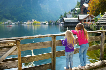 Two girls enjoying the scenic view of Hallstatt lakeside town in the Austrian Alps in beautiful evening light on beautiful day in autumn